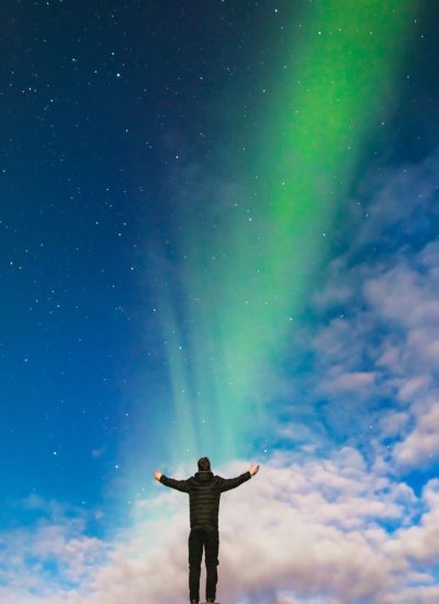 Man standing with open arms under the northern light.